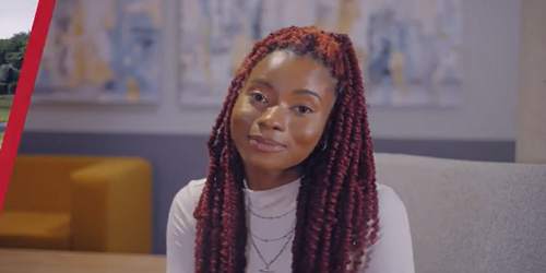 A young woman sitting and smiling at the camera.